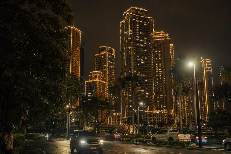 High-rise towers wrapped in warm golden Christmas lights glowing against the Makati night sky