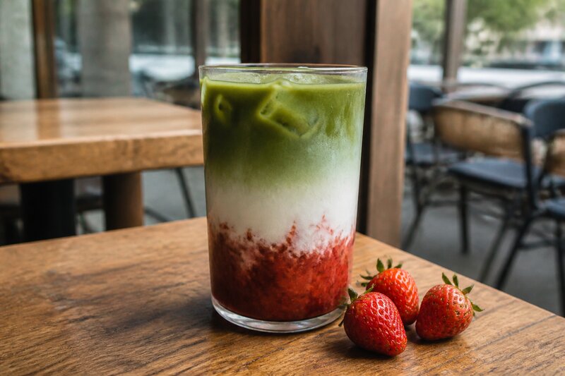 A strawberry matcha latte with layers of red strawberry puree, milk and green matcha