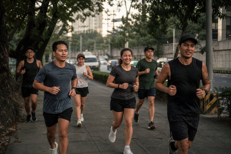 Runners jogging together along a tree-lined city promenade in the early morning
